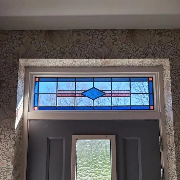 Bovenlicht met blauw glas in lood en een ruit in het midden, uitgevoerd in dubbelglas boven een voordeur