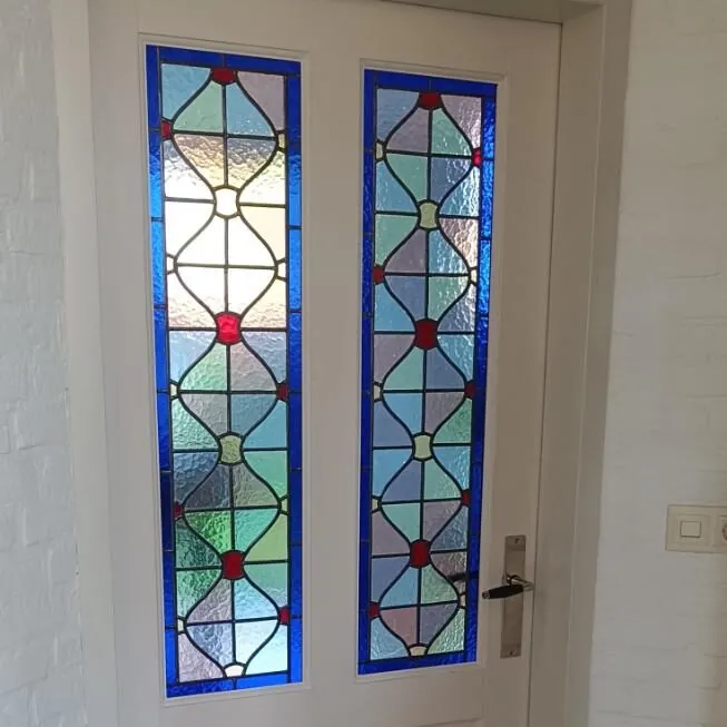 Twee smalle glas-in-loodpanelen naast een deur, met blauw, rood en heldere ruiten