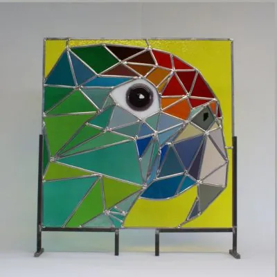 Glas-in-lood papegaai in groen, geel, rood en blauw