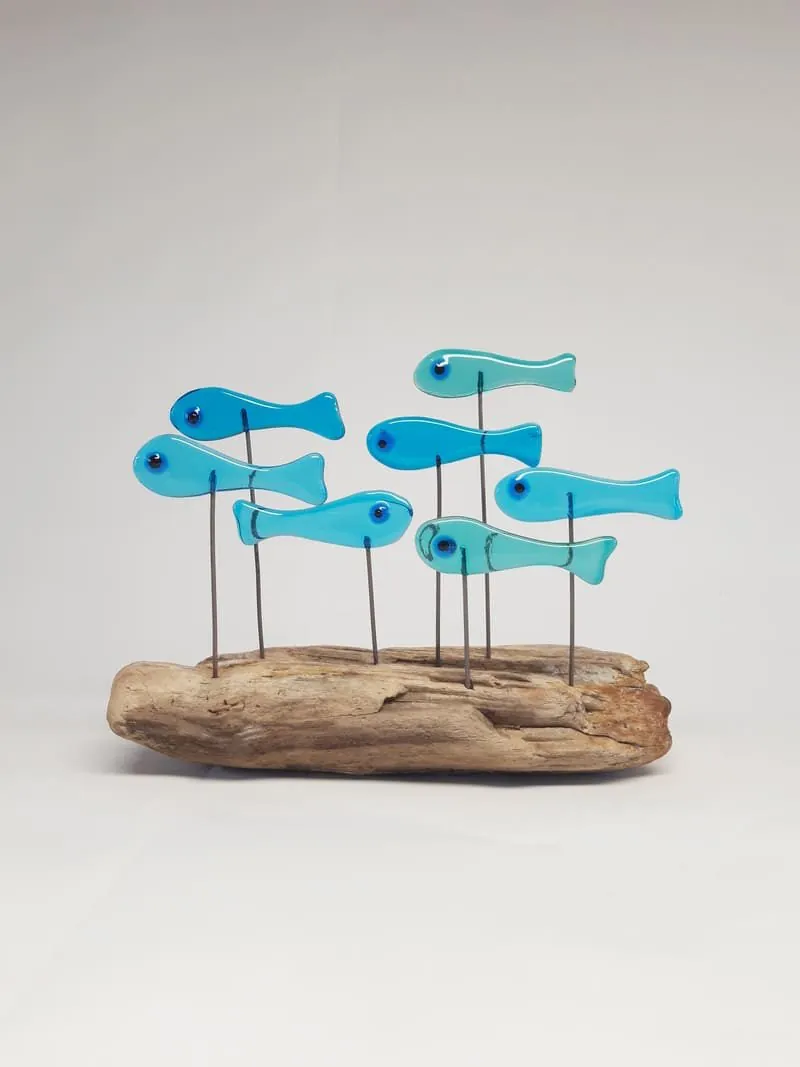 Blauwe glazen visjes op een stuk drijfhout